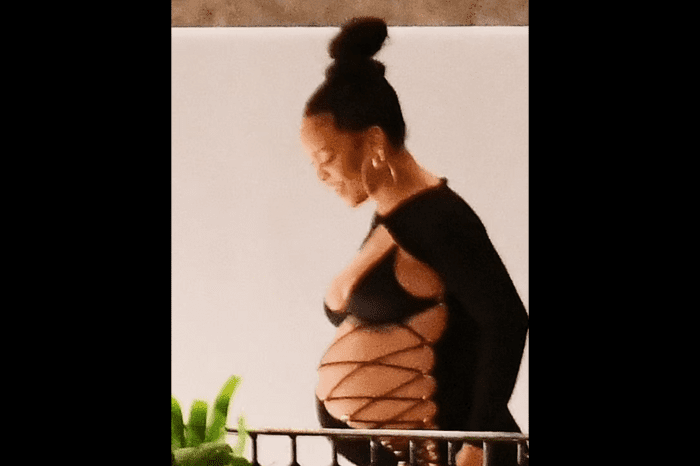 Rihanna proudly shows off her growing belly in a slit dress